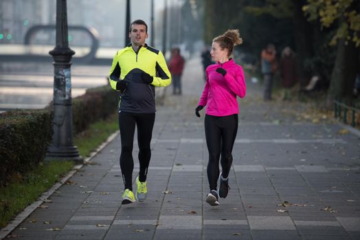 healthy young  couple jogging in the city  at early morning with sunrise in background