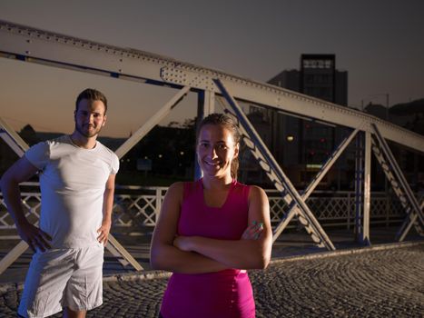 urban sports, portrait of a healthy couple jogging across the bridge in the city at early morning in night