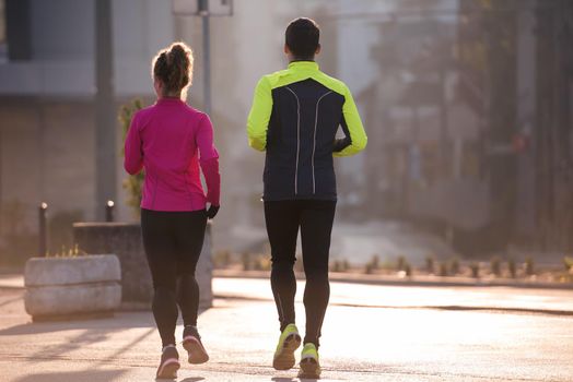 healthy young  couple jogging in the city  at early morning with sunrise in background