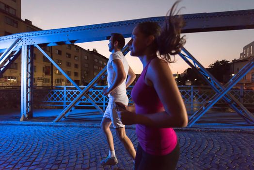 urban sports, healthy couple jogging across the bridge in the city at early morning in night