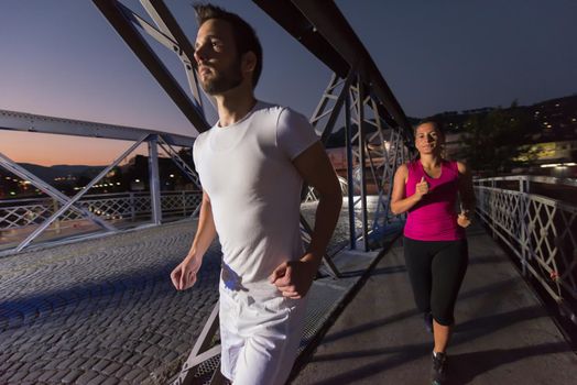 urban sports, healthy couple jogging across the bridge in the city at early morning in night