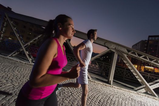 urban sports, healthy couple jogging across the bridge in the city at early morning in night