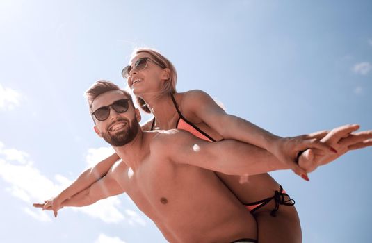 Handsome man giving piggy back to his girlfriend.