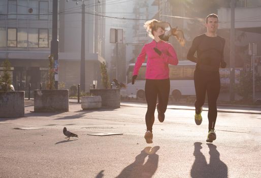 healthy young  couple jogging in the city  at early morning with sunrise in background