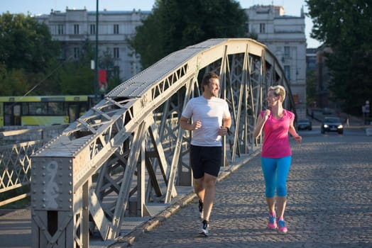 healthy mature couple jogging in the city  at early morning with sunrise in background