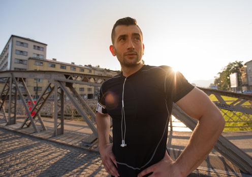 portrait of a young sporty jogging man at sunny morning in the city