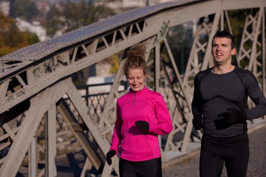 healthy young  couple jogging in the city  at early morning with sunrise in background