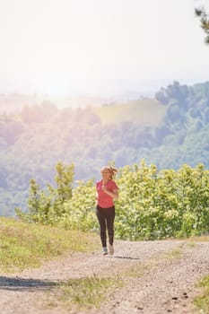 woman enjoying in a healthy lifestyle while jogging on a country road through the beautiful sunny forest, exercise and fitness concept