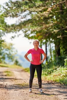 woman enjoying in a healthy lifestyle while jogging on a country road through the beautiful sunny forest, exercise and fitness concept