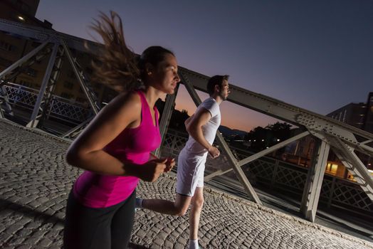 urban sports, healthy couple jogging across the bridge in the city at early morning in night