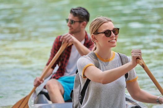 Couple adventurous explorer friends are canoeing in a wild river surrounded by the beautiful nature