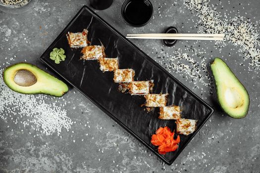 sushi rolls with cream cheese, fried salmon, tuna shavings or dried bonito, cucumber, nori. Chopsticks holding fresh katsuobushi roll in Japanese restaurant closeup.