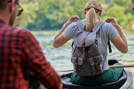 Couple adventurous explorer friends are canoeing in a wild river surrounded by the beautiful nature