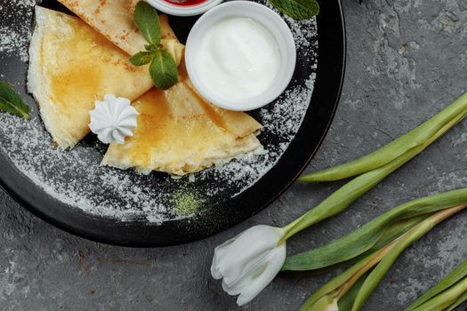 Pancakes with strawberries and creme black plate.