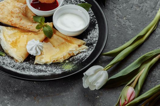 Pancakes with strawberries and creme black plate.