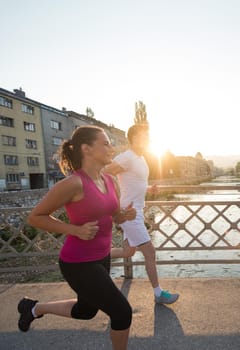 urban sports, healthy young couple jogging across the bridge in the city at sunny morning