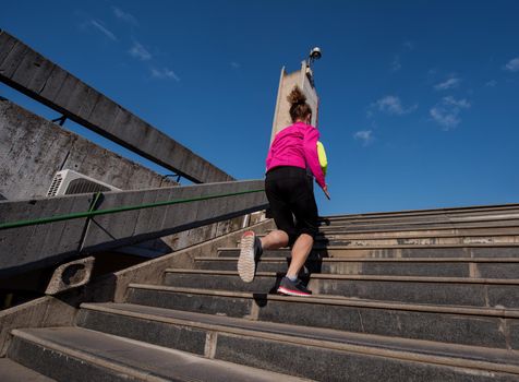 sporty woman running onsteps at early morning jogging