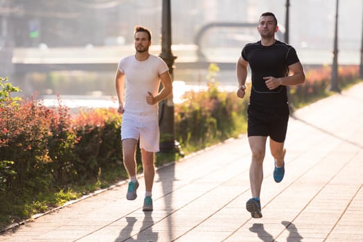 group of young sporty people jogging at sunny morning in the city