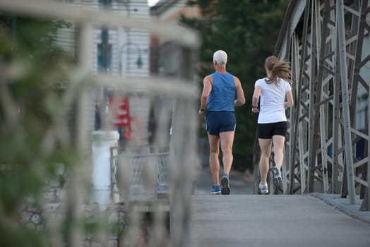 healthy mature couple jogging in the city  at early morning with sunrise in background