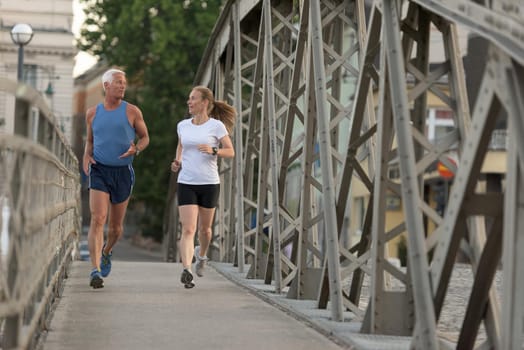 healthy mature couple jogging in the city  at early morning with sunrise in background