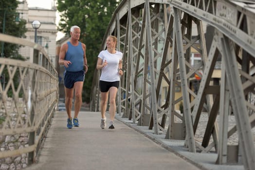 healthy mature couple jogging in the city  at early morning with sunrise in background