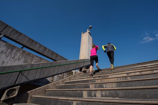 healthy young  couple jogging on steps  at early morning