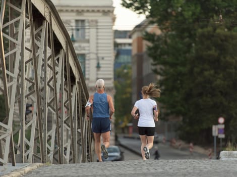 healthy mature couple jogging in the city  at early morning with sunrise in background