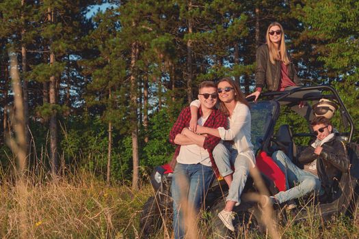 portrait of group young happy people enjoying beautiful sunny day while driving a off road buggy car on mountain nature