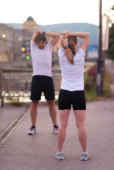 jogging couple warming up and stretching before morning running in the city