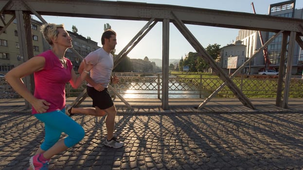 healthy mature couple jogging in the city  at early morning with sunrise in background