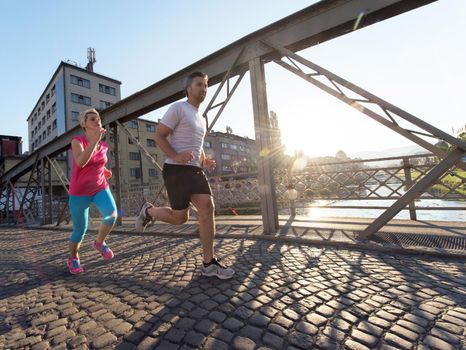 healthy mature couple jogging in the city  at early morning with sunrise in background