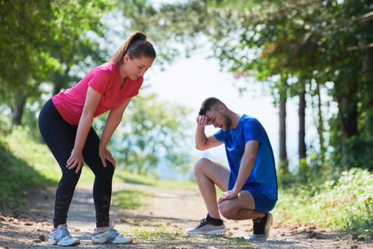 young happy couple enjoying in a healthy lifestyle while jogging on a country road through the beautiful sunny forest, exercise and fitness concept