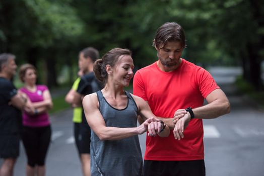 Young sporty couple using smart watches starting their timer before jogging