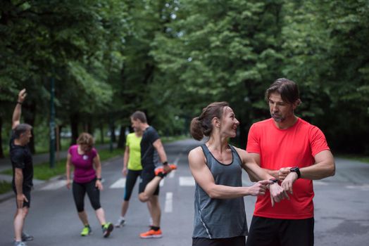 Young sporty couple using smart watches starting their timer before jogging