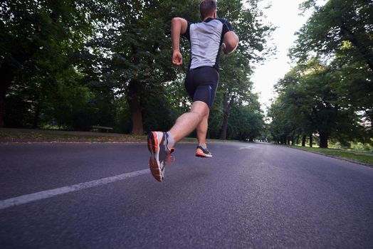 healthy athlete man jogging at morning on empty  roat in the city