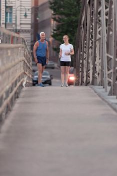 healthy mature couple jogging in the city  at early morning with sunrise in background