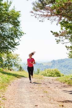 woman enjoying in a healthy lifestyle while jogging on a country road through the beautiful sunny forest, exercise and fitness concept