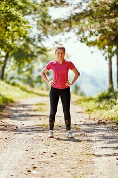 woman enjoying in a healthy lifestyle while jogging on a country road through the beautiful sunny forest, exercise and fitness concept