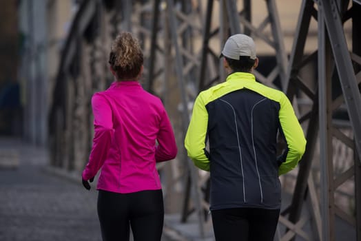 healthy young  couple jogging in the city  at early morning with sunrise in background