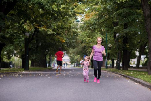 young sporty mother and little daughter jogging in a city park outdoor sports and fitness