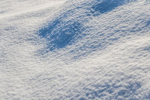 Hilly surface covered with fresh snow in the garden on a sunny day. Natural winter background.