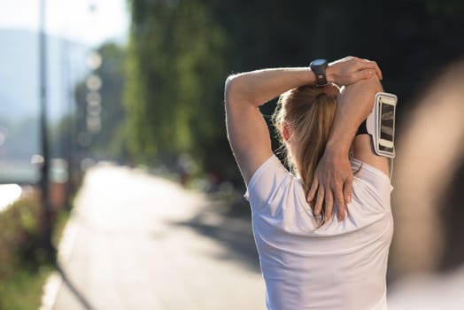 Fit blonde runner   woman warming up and stretching before morning jogging