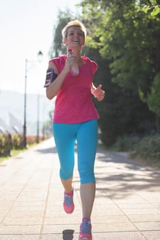 sporty woman running on sidewalk at early morning with city  sunrise scene in background