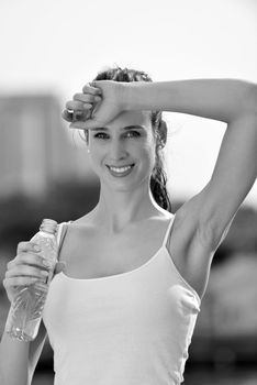 Young beautiful woman drinking water after fitness exercise and jogging outdoors