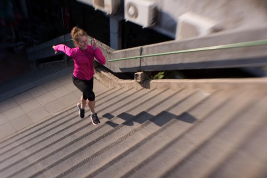 sporty woman running onsteps at early morning jogging