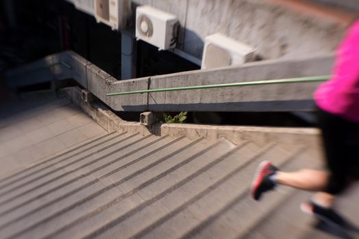 sporty woman running onsteps at early morning jogging