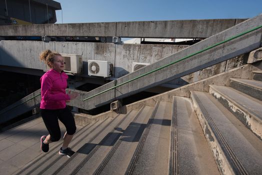 sporty woman running onsteps at early morning jogging