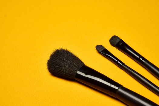 cosmetics mascara brushes decoration accessories yellow background. High quality photo