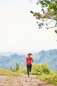 woman enjoying in a healthy lifestyle while jogging on a country road through the beautiful sunny forest, exercise and fitness concept