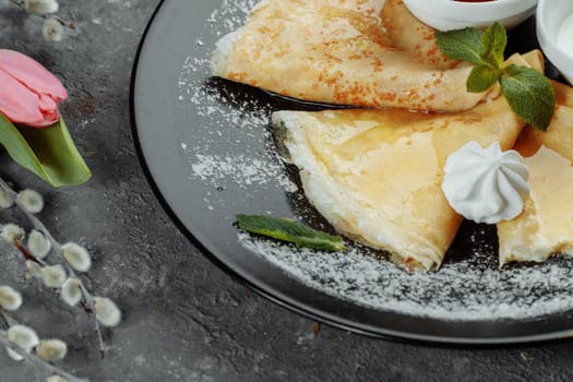 Pancakes with strawberries and creme black plate.